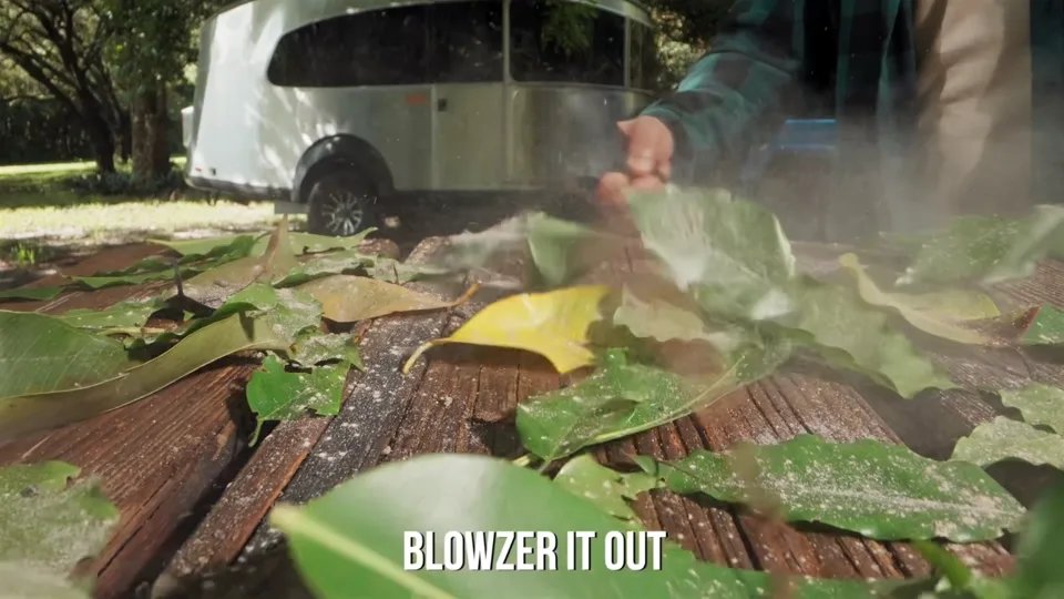 Supplied BLOWZER product footage: the SABRENT BLOWZER X6 handheld blower clearing leaves from a deck on an RV trip.